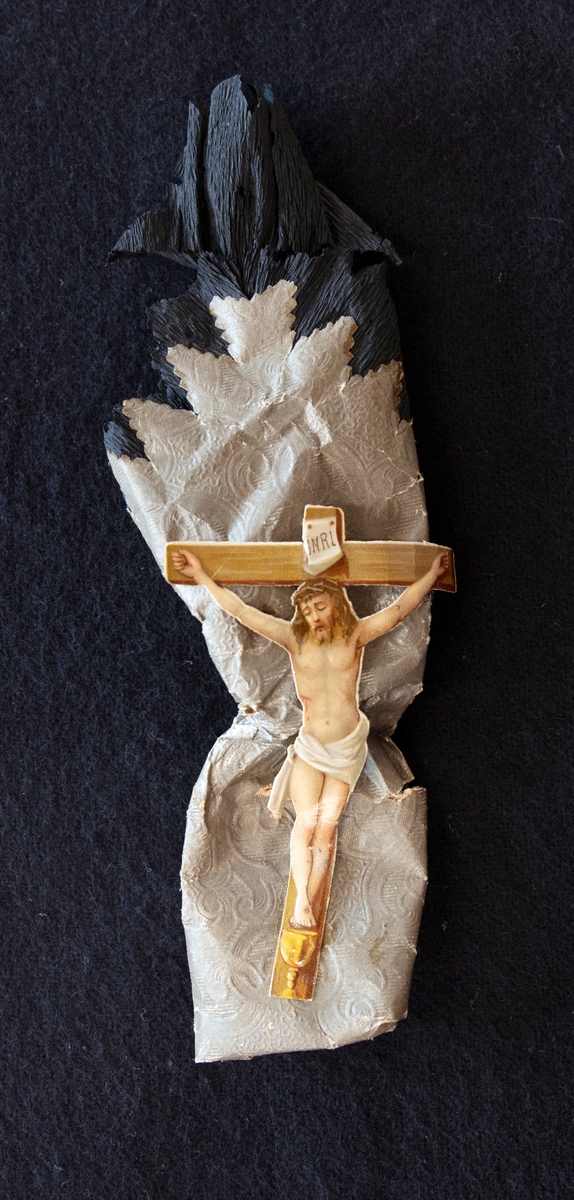 Begravningskaramell. Silverfärgat papper med svart kreppapper. Ett bokmärke med Jesus på korset finns fästat på pappret. Sötsaken är borttagen.

En av en samling karameller för dop-bröllop och begravningar.