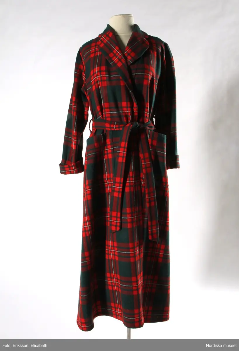 Morgonrock, 1950-60-tal, engelskt fabrikat av kyprat skotskrutigt ylle.
Grön botten med rutor i rött, vitt och svart. 1 bakstycke, 2 framstycken. Krage med 2 rundade slag. Knytskärp i midjan. 1 påsydd ficka på var sida. Ärmarna med påsytt uppslag. 
Inköpt på MEA.