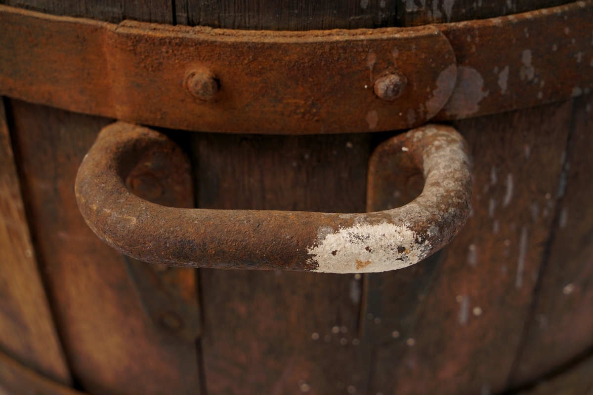 Tretønne (hektolitermål) med 2 bærehanker av metall,.Tønnen er utvendig forsynt med fire metallringer.