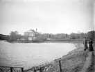 Vy mot Norsholms nya herrgård invid Roxens östra strand. Dokumenterad av den flitige amatörfotografen tillika översten Lars Fredrik Lovén 1893-94. Herrgården uppfördes 1865-66 efter ritningar av Axel Kumlien. Vid tiden för bilden ägdes gården av kapten Axel Abelin med makan Eva Elisabeth. Möjligen är det dem som ses till höger.