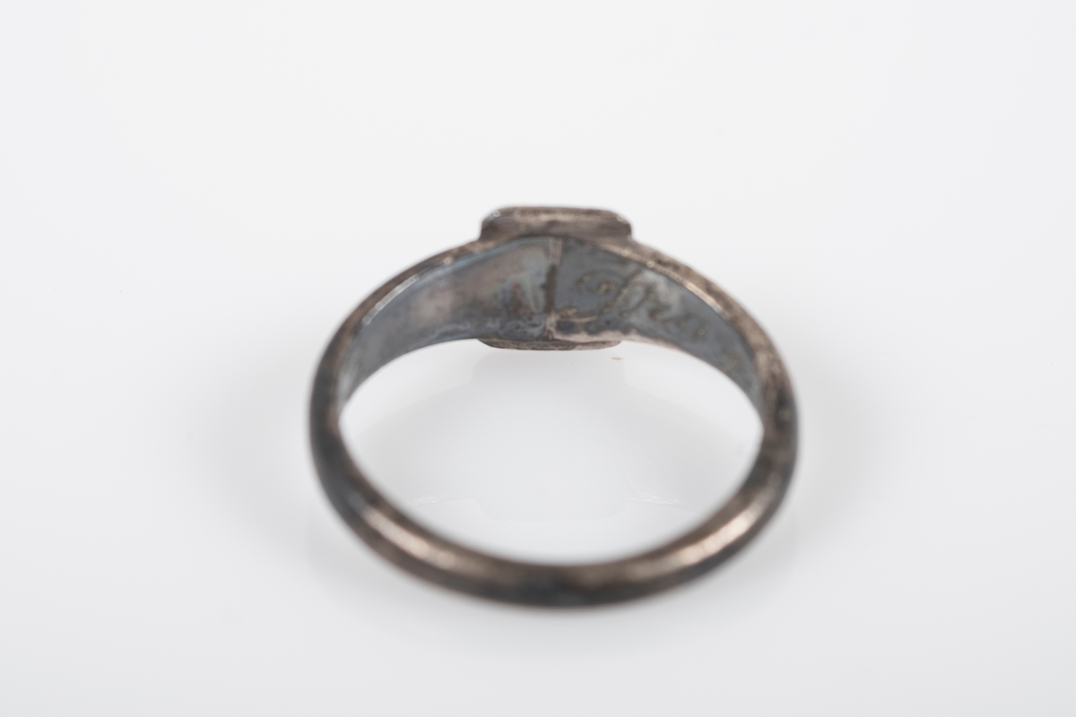 Liten rund ring med et firkantet monogram foran med initialene BL inngravert. På innsiden er det inngravert "Fra Far Grini 1942-43".