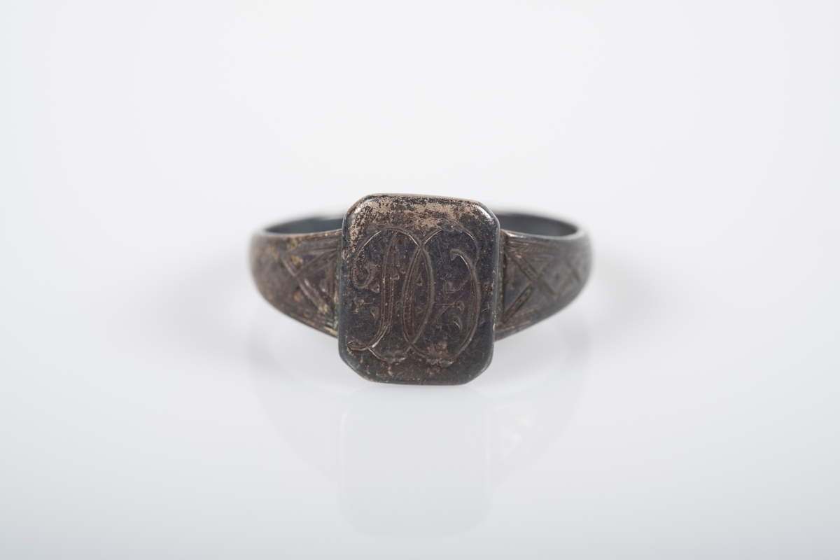 Rund ring i med et firkantet monogram hvor initialene D.O er inngravert. På innsiden står det Grini 1943.