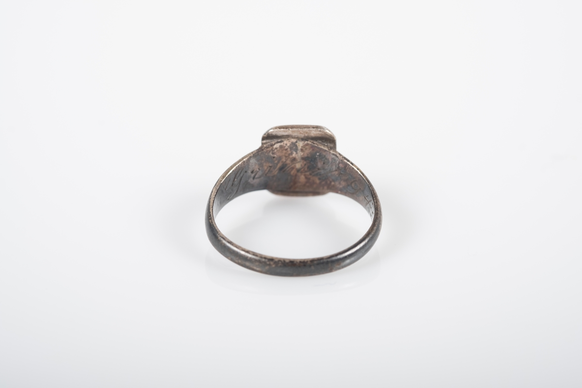 Rund ring i med et firkantet monogram hvor initialene D.O er inngravert. På innsiden står det Grini 1943.