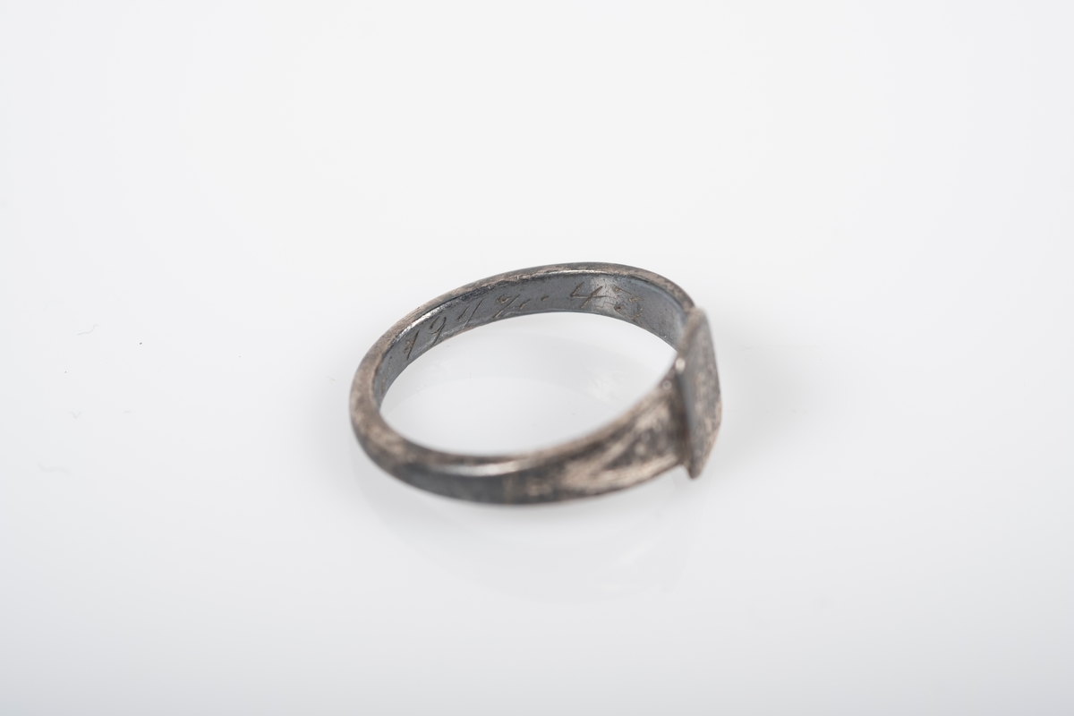 Liten rund ring med et firkantet monogram foran med initialene BL inngravert. På innsiden er det inngravert "Fra Far Grini 1942-43".