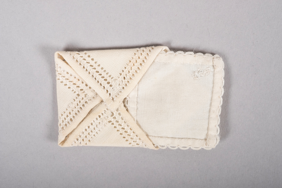 To små tøybiter sydd som et brev og en konvolutt.

"Konvolutten" er pyntet med hullbroderier og det står brodert:
"5/7
GRiNi.
1944"

"Brevet" har en heklet kant og et brodert "G".