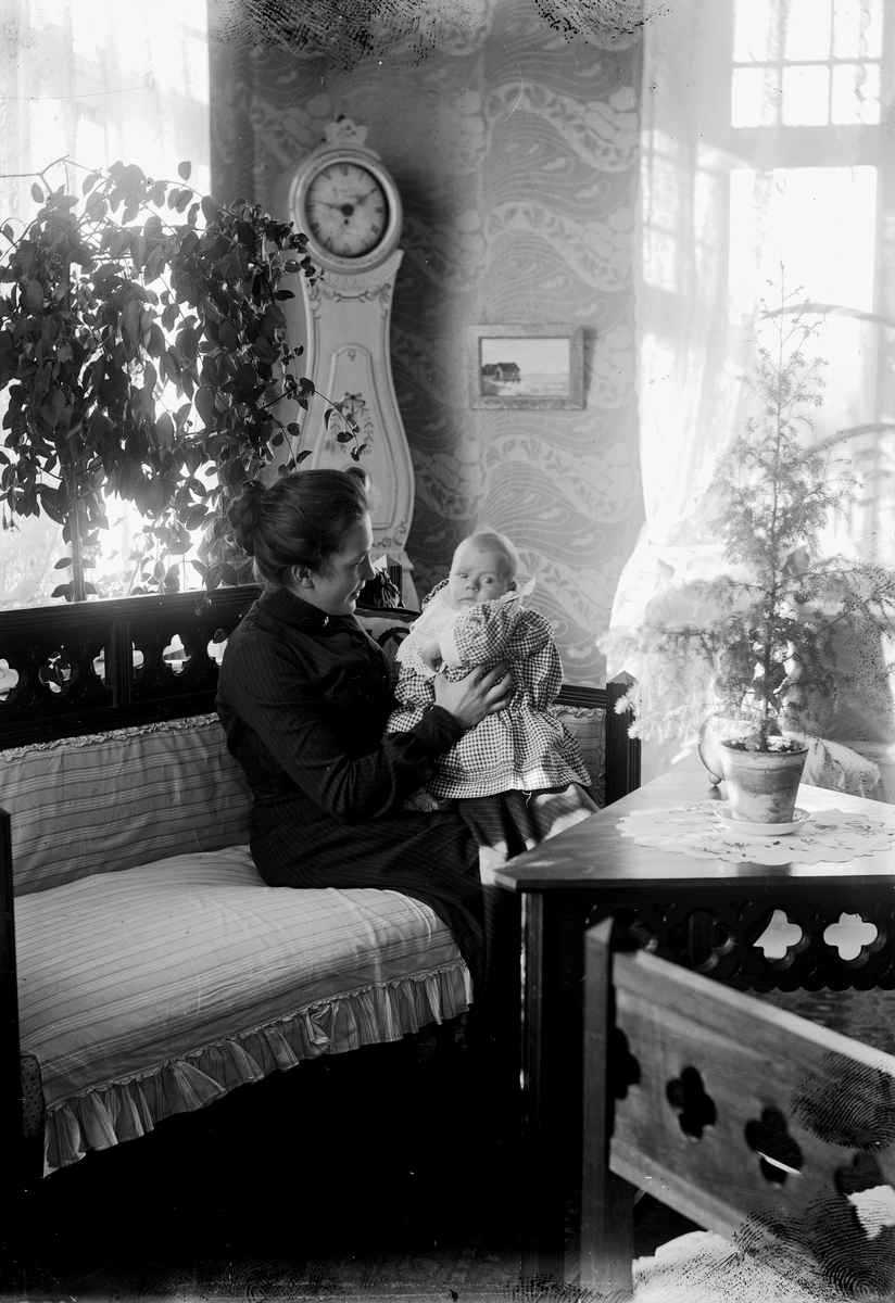 Rumsinteriör, en kvinna med ett litet barn i soffan.
Sigrid Thermaenius (född Grenander) med sonen Olof (Olle) Thermaenius, född 1902-08-30.
Bilder från samma fototillfälle: OLM-92.149.128-1 och OLM-92.149.157-1