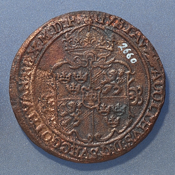 Rundmynt, 1 öre.
Åtsidan: mitt på myntet är det svenska riksvapnet, svagt och delvis synligt.
Omskriften, med Gustav Adolfs titlar på latin, är svagt, delvis synlig men till största delen oläslig.
Ocentrerad prägling.
Frånsidan: en örn framifrån med utbredda vingar, svagt, delvis synlig. Under örnen siffran 1 och versalerna ÖR, svagt, delvis synliga. Omskriften på latin, med bland annat präglingsåret 1627, är till största delen oläslig.
Nuvarande skick: bägge sidor slitna, jack valsklump, korroderat.