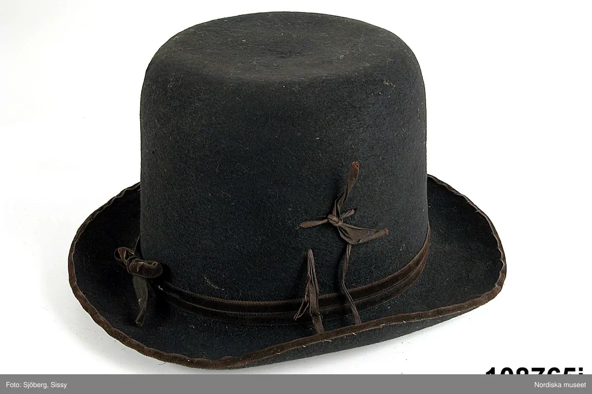 Hel mansdräkt bestående av 12 delar.
a. skjorta
b. rock av svart kläde
c. väst av svart kläde
d. knäbyxor av sämskskinn
e. förskinn
f. 1 par strumpor vita
g. handskar av sämsskinn
h. 1 par skor
i. hatt
j. hatt
k. långhalsduk
l. löskrage.
/BEEL

a. Mått: längd: 96 cm. Längd: 52 cm - ärmlängd. Vidd: 52 cm - ärmvidd
Material: Textil, linne. Lingarn - broderier, band. Teknik: Handvävning. Gåsögon. Trådbundet broderi. Broderi - plattsöm. Handsömnad
Rak mansskjorta i handvävt hellinnetyg, vävt i gåsögon.  Båltyget i ett stycke, sidosömmar med 13 cm långa sidosprund. Öppning fram, 31 cm långt sprund. Rektangulärt halsspjäll,  rynkningar mot 8,5 cm hög krage med broderier på både in- och utsida i kanten, plattsöm och trädsöm, nuggor i katnen. Två fastsydda mönstervävda knytband, blå/vit och vit. Vidsydd ärm med ärmspjäll. Rynkningar mot 1,3 cm bred ärmlinning broderad med plattsöm och trädsöm, nuggor i kanten,  mönstervävda knytband.. Skjortan är handsydd.
/Inga-Lill Eliasson 2007-04-17


f. 1 par strumpor  skaftlängd 40 cm, fot 26 cm; tvåändsstickade av vitt ullgarn i slätstickning.
g.
h.
i.
j.Hatt, svart rundkullig filthatt, kullens höjd 14 cm, brätte bredd 5 cm; lätt uppböjt brätte kantat med bomullsband, delvis fodrad med ljust bomullstyg.
/BEEL
k.Längd: 139 cm. Bredd: 18,5 cm. Material: Halvlinne. Telnik: Handvävning, dräll. Handsömnad.
Långhalsduk vävd i dräll, avlång,  randigt mönster av ca 1,3 cm breda ränder i dräll med tuskaft emellan. Handsydd smal fållad kant.
Anm: Något gulnad.
/INEL.
l. Löskrage "hassdutj" längd 34 cm, bredd 8,7 cm, rak remsa av vit fin linnelärft, broderi i plattsöm längs långsidorna med små "nuggor" i kanten. Baksida av en bit linneväv med ränder i kypertvariation, knytband i ändarna av mönstervävt linneband i ljusgrått och vitt.

Berit Eldvik maj 2006