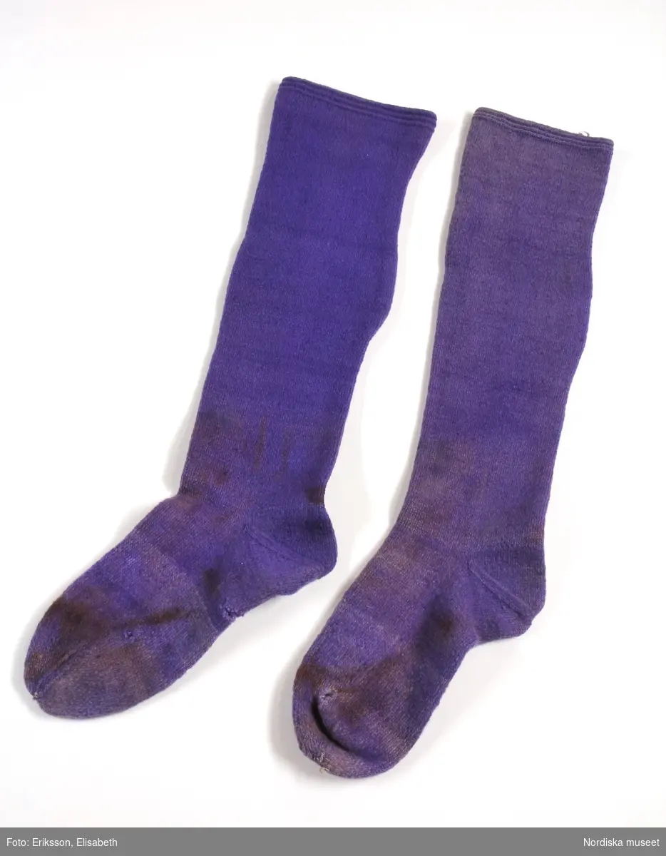 Mansdräkt från Floda sn bestående av:
a. blå vadmalsrock "blåtröja"
b. knäbyxor av sämskskinn, längd bak 90 cm, luckans br: 28 cm
c. väst av mörkblått kläde, längd bak 42 cm, fram 37 cm,
d. 1-2 ärmmuddar
e. strumpor
f. strumpeband, 
g. skjorta, 
h. nattkappa

Bilaga:
Finns ej.

Katalogkort:
g: "Skjorta. Längd: 102 cm. Axelbredd: 65 cm. Rakskuren. Hela framstycket av hellinne, ryggstycket av halvlinne. Ett 26. cm långt sprund framtill med ett veck, som döljer sprundet. 2 knapphål och 2 vita porslinsknappar. Skjortan rynkad vid kragen, vilken är 46 cm. lång och 9,5 cm. bred. Ett 9 cm långt sprund nedtill i varje sida. Ärmens längd 58 cm., vidd 49 cm. med spjäll. Ärmen nedtill rynkad vid den 3,7 cm. breda, med rätlinjig plattsöm broderade linningen. En vit porslinsknapp, ett knapphål."

b. KNÄBYXOR av sämskskinn, 2 fram-och 2 bakstycken midjegjord infodrad med svartrandig bomullskypert, sprund mitt bak, knäppt med 2 mässingsknappar, 4 hängselknappar, lucka av ovanligt slag med dubbla knapprader med 10 mässingsknappar, rikligt ornerade laskningar på luckan och på knäna med stjärnmönster, bensprund med 4 par hakar och hyskor av mässing, benlinningar för knäspännen, knälapp nedhängande.
c.VÄST 2 framstycken av mörkblått kläde, ett bakstycke av randigt bolstervarstyg i bounll i beige, rödbrunt, blått, gult, gråbrunt, gulbrunt och vitt. 2 iskurna fickor med 4,3 cm breda slåar. Dubbelknäppt med 16 svarta knappar och knapphål, en knapp har saknats är nu ersatt med annan knapp. Foder av kyprtat bomullstyg.
Berit Eldvik 2004

g: Längd: 102 cm. Längd: 58 cm - ärmlängd. Bredd: 46 cm - krage. Höjd: 9,5 cm - kraghöjd. Vidd: 112 cm. Vidd: 48 cm - ärmvidd.
Mansskjorta av kypertvävt linne i framstycket och kypertvävt halvlinne i bakstycket, övergången mellan hel- och halvlinne sker 6 cm nedanför axeln på framstycket. Traditionelll modell med dubbelvikt bålstycke, 9 cm långt sprund i sidorna. Rektangulärt halsspjäll med rynkningar mot krage. Dubbelvikt krage av fint helline, 9,5 cm hög, 2 porslinsknappar på insidan. Förslag med  syttknapphål, längd: 26 cm, bredd: 10 cm. Vidsydd kypertvävd ärm i halvlinne med ärmspjäll. Rynkningar mot 3 cm bred ärmlinning med plattsömsbroderi i rombiska mindre former, vitt bomullsgarn, vit porslinsknapp och  sytt knapphål. Skjortan är handsydd.
/Inga-Lill Eliasson 2006-11-13

h: Nattkappa av tuskaftat vitt bomullstyg. Tre stycken, ett långt, 23 cm, och två kortare 9 cm på var sida, hopsydda och rynkade mot 9 cm hög krage som dubbelviks. Två cm bred broderad kantbård upptill, vinklar och små rombiska former i  rätlinjig plattsöm, vitt lingarn. Langetterade bågar utmed kanten. Nattkappan är handsydd, smala fållade kanter.
Anm: Gulnat.
/Inga-Lill Eliasson 2006-11-21