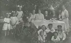 Gruppfoto på Skeviksgatan.
Personer: Fr v: Margit (Söderlund) Fall, Märta Gradin, Astrid Mattsman, Ingegerd Holmberg, Anna Gehlin, Berta Holmberg, Lilly Eriksson, Abel Holmberg, Elin Lindholm, bakom henne Alrik Trygg med son Olle, Johan Lindholm, Alrik Trygg<br>Sittande fr v: Gunnar Fall, Herman Fall, Bertil Holmberg, Fritiof Fall, Axel Fall