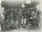 Gruppfoto. Okänd plats. Verkmästare och förmän i första hand på HPF och konstavdelningen.
Personer: Bilden visar bl a Berndt Friberg, Lennart Elofsson (med dragspel) Calle Blomqvist (med mandolin), Harry Pettersson, Oskar Wadström.