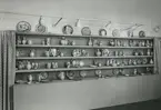 Interiörbild. Utställning med föremål från Gustavsbergs fabriker. Fat och vaser. Fajanser målade i rödlera, polykrom dekor. Konstnärer: Wilhelm Kåge och Stig Lindberg. 1942. Plats okänd.