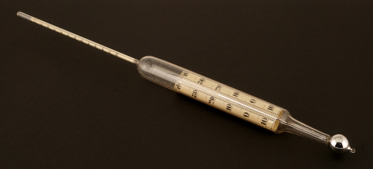 Flytevekt av glass  som ligger i et rundt etui av formentlig papp.