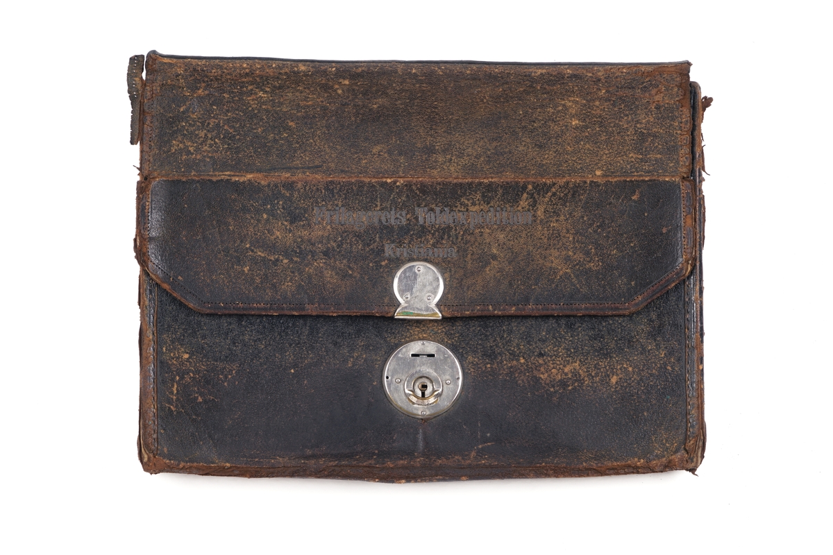 Veske av sort lær foret med tekstil/lerret, og med pappforsterket låsbart lokk . Låsedelen på lokk og veske er av metall. Nøkkel er borte. Vesken inneholder formentlig rester av plomberingstråd og to blyplomber. De smale hyssingen er antakelig brukt som forseglingstråd i tiden før forseglingstråden ble flerfarget. Medfølgende sammenkrøllede papir er antakelig brukt for å omslutte blyplomber.