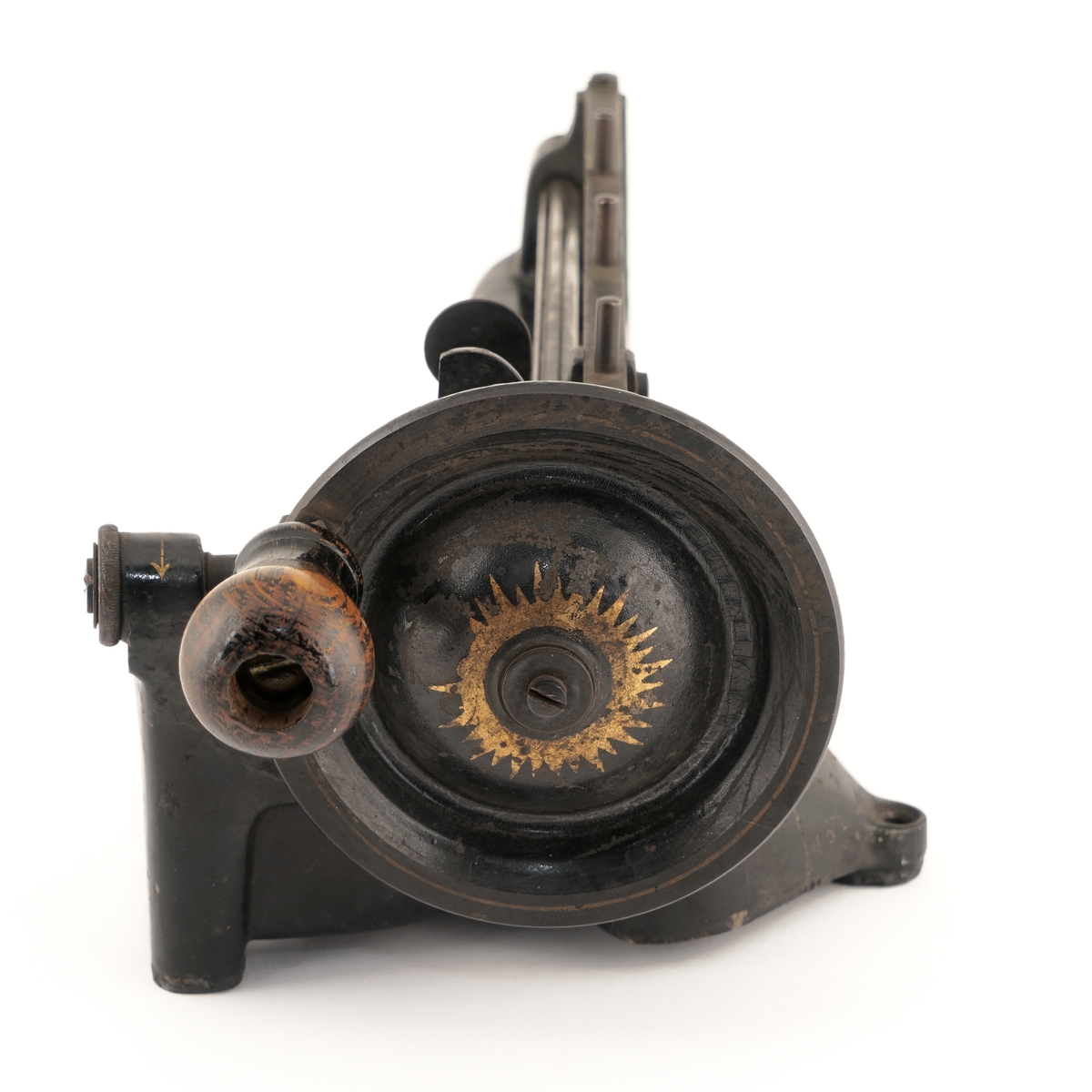 Blyantspissemaskin  av metall, sortlakkert med påskrift i gullfarge. Dreiet trehåndtak.