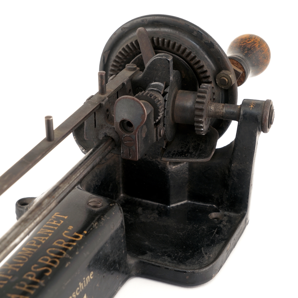 Blyantspissemaskin  av metall, sortlakkert med påskrift i gullfarge. Dreiet trehåndtak.