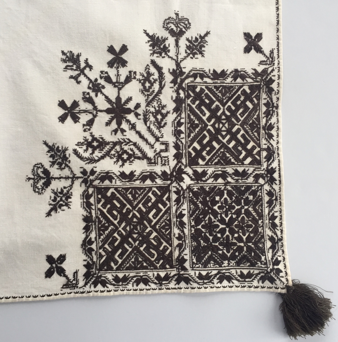 Blomsterinspirerat mönster i kvadrater i hörnen. Runt kvadraterna bård i blomstermotiv. Mellan kvadraterna på ryggsnibb och framsnibbar blomsterdekoration.  På ryggsnibben tre kvadrater och en dekorerad  majstångsspira. På varje framsnibb en kvadrat och en trekant.