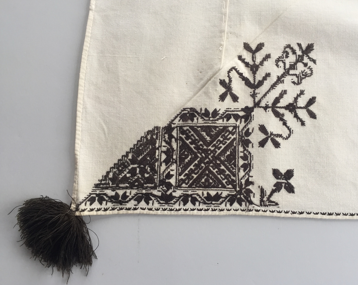 Blomsterinspirerat mönster i kvadrater i hörnen. Runt kvadraterna bård i blomstermotiv. Mellan kvadraterna på ryggsnibb och framsnibbar blomsterdekoration.  På ryggsnibben tre kvadrater och en dekorerad  majstångsspira. På varje framsnibb en kvadrat och en trekant.