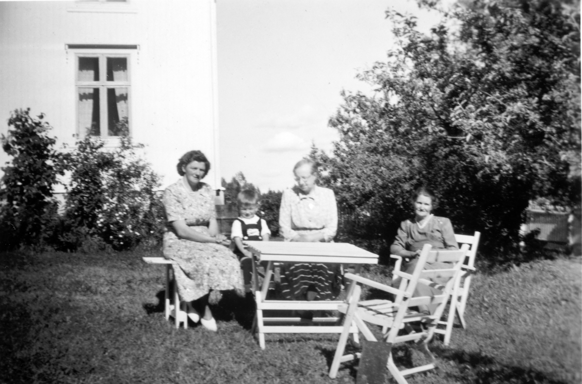 Lilletomter (60/8). Fra hagen der Sigrun Tomter (i midten) har besøk av Karen Tomter (t.v.) og sønnen Ole Jacob. Til høgre sitter muligens Gønner Toresen, den gamle husholderen til Kristoffer Tomter. Han bodde her til sin død i 1941 og Gønner ble boende på «Gønnerkammerset» fram til hun kom til Finsal. Ca 1953.