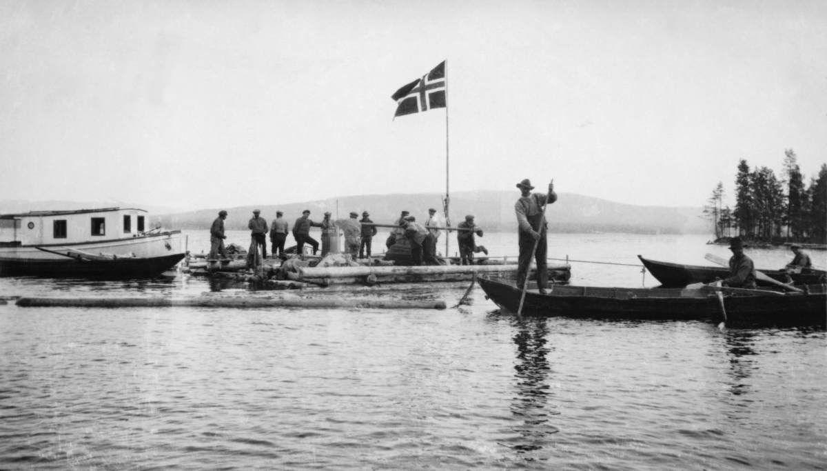 Spillflåter i virksomhet på Osensjøen i 1921.  Fotografiet viser to flåter som ligger inntil hverandre, den ene med vaiende norsk flagg.  På denne flåten «danser» fire karer rundt gangspillet, og trossa står stram mot et ankringspunkt lengre framme i sjøen (til høyre på fotografiet).  Her ligger to robåter.  I den nærmeste sitter en kar ved årene, mens en annen står i akterenden med fløterhaken sin.  Bak båten skimtes ei lense.  Bakenfor ligger nok en robåt, muligens den som ble brukt til å ro dreggen (ankeret) framover i sjøen med, når spillflåten og den bakenforhengende tømmerbommen skulle bukseres i en bestemt retning.  Bakenfor spillflåtene ligger en kvitmalt motorbåt med forholdsvis stort oppbygg (styrhus) på dekk. 

Fotografiet skal være tatt sju år etter at dampbåten Trysil-Knut ble tatt i bruk som tømmersleper på Osensjøen.  På denne tida ble spillflåter og småbåter antakelig bare brukt i forbindelse med varping langs strendene.