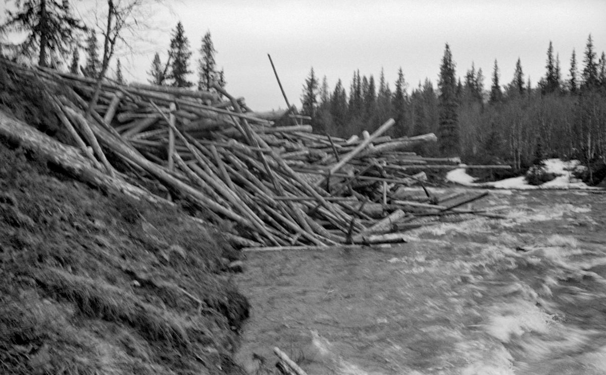 Utislag i elva Lebba, ved et sted som kalles Svanvollan, i Sør-Fron kommune, like nord for kommunegrensa mot Gausdal.  Fotografiet er tatt i midten av mai 1957.  Tømmeret var øyensynlig veltet utfor elveskråningen, hulter til bulter, på en måte som antakelig gjorde det arbeidskrevende å få det til å flyte videre.  Lebba ligger i den øvre delen av den østre greina av Gausavassdraget, som kommer fra Fagerlivatnet på grensa mellom Nord- og Sør-Fron.  Denne elva renner videre gjennom Vestre Gausdal, før den dreier østover mot Follebu, og ender til slutt i Gudbrandsdalslågen i Fåberg, en strekning på bortimot sju mil.