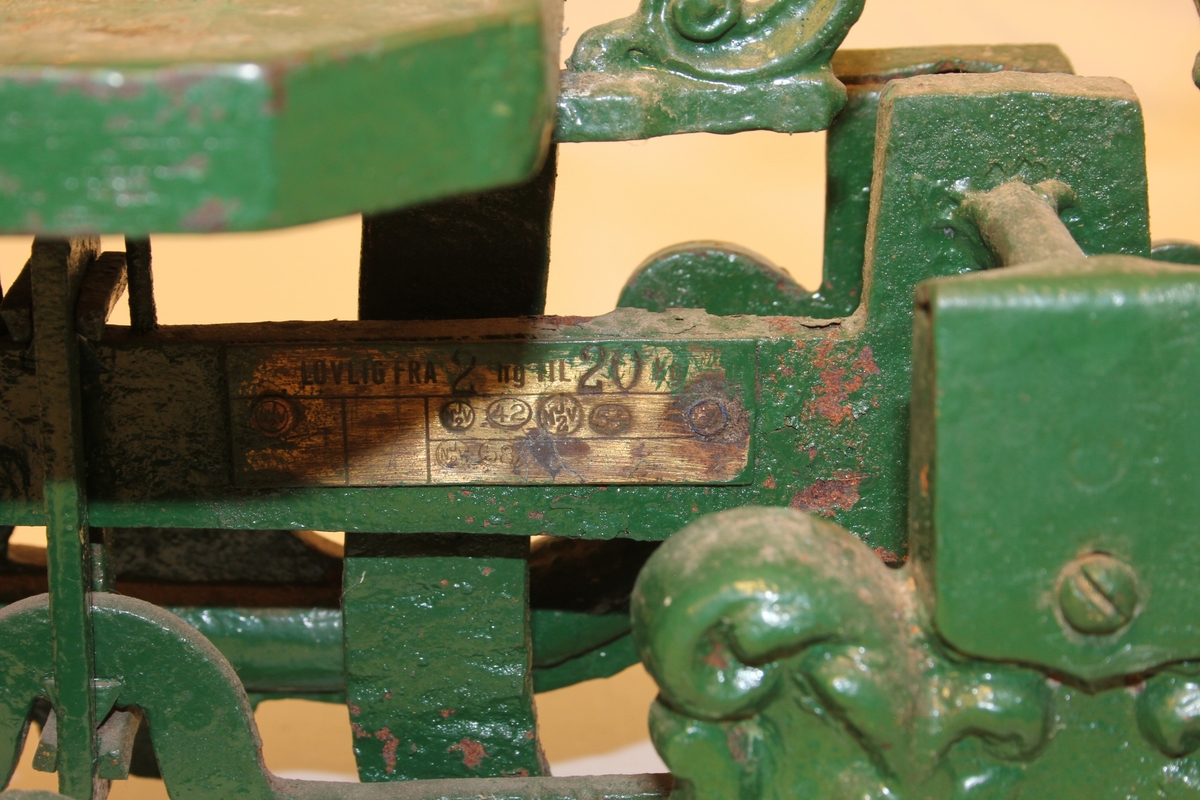 Diskvekt med to skåler. Fire føter med form av dyr-/menneskeskikkelsar. To dyrefigurar med tunger som viser når vekta er i balanse.