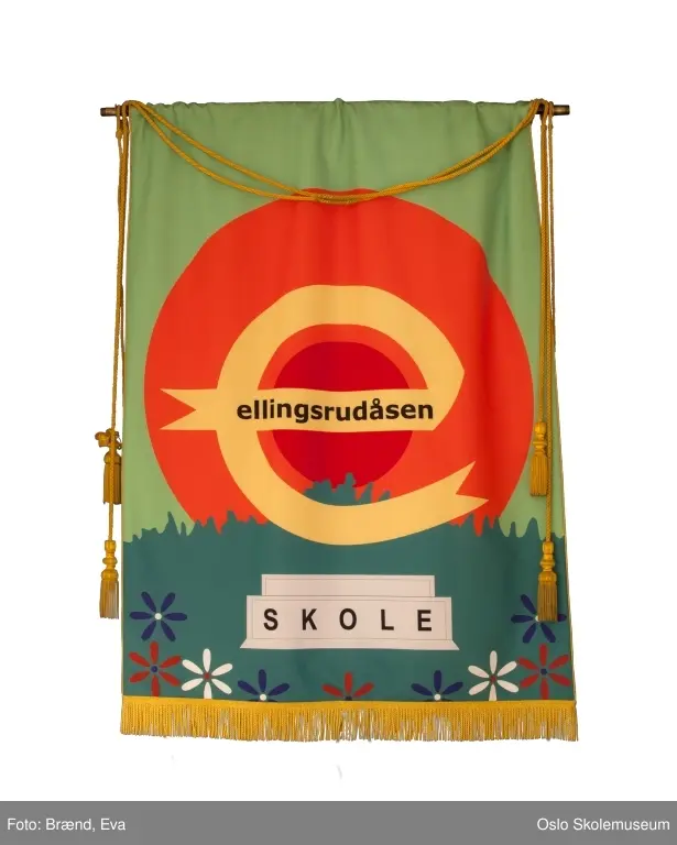 En "e" for Ellingsrud i sentrum mot en oransje sol og gresskledd slette i bakgrunnen. Skolens navn står også på fanen.