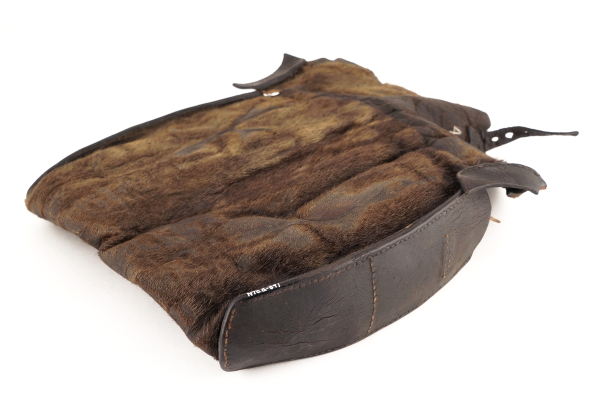 Veske av selskinn hvor det på lokket er festet en lærrem med hull. På vesken er det rester etter antatt låseanordning for lærremmen på lokket. Hovedrom i vesken er delt i to med selskinn. i det ene rommet er det en rull med rød/blå/hvit tråd av bomull (plomberingstråd). I det andre rommet ligger det tre blyplomber.