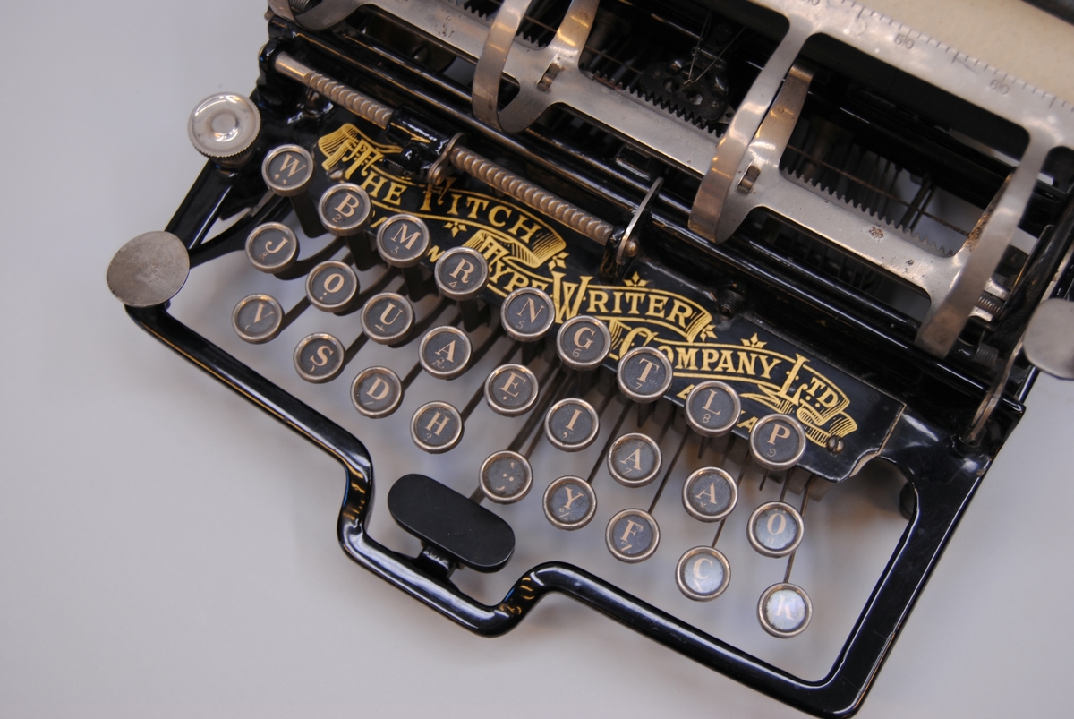 Skrivmaskin av amerikanen Fitchs patent, där typerna är placerade ovanför och bak maskinen och slår mot valsen uppifrån. Maskinen är av stål och svartlackad metall, med detaljer i guld. Valsen är klädd med svart gummi. Ett gulnat papper sitter kvar kring valsen.

Modell/Fabrikat/typ: 3057
