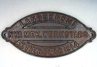 Mandelformad skylt av rostbrunt gjutjärn med text i relief.