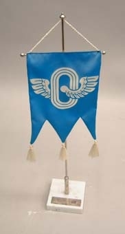 Bordsstandar med blå treflikig flagga. I mitten tryck av en vit bevingad oval. Vita tofsar nertill. Sockel av grå marmor med en silverplatta med följande text på finska:
"Tennis
Ruotsi-Suomi
Örebro  7.6.1980
VR Urheilu".

Ungefärlig översättning: "Tennis Sverige-Finland Örebro 7.6.1980 VR idrott".