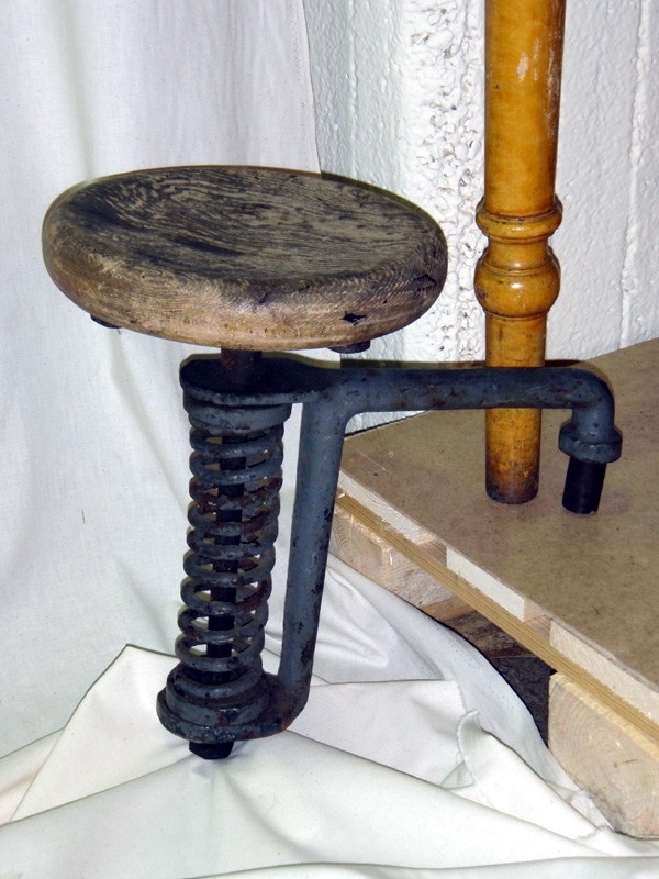 Cirkelrund sits av trä på grålackerat järnrör som sitter inuti en metallfjäder, vilken ger stolen fjädring. Med hjälp av gängor kan röret skruvas upp och ned i höjdled och på så sätt kan sitsen höjas och sänkas. Ytterligare ett järnrör, ett grövre, går i rät vinkel ut från sistenoch dess underrede. Med detta rör har stolen suttit fast i lokväggen. 
   Har använts som stol till förare av ånglok. Det sista ånglok som tillverkades med den här typen av lokförarstol, stod klar 1947. Denna förarstolstyp ersattes sedermera av en skrivbordsliknande stol i plywood med ryggstöd.