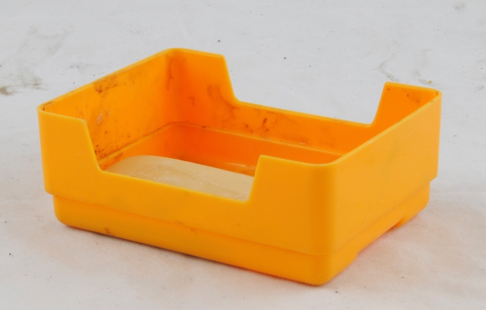 Lock till tvålask av gul plast. (Underdel, se Jvm 20555:3). Asken innehåller en liten använd tvål.