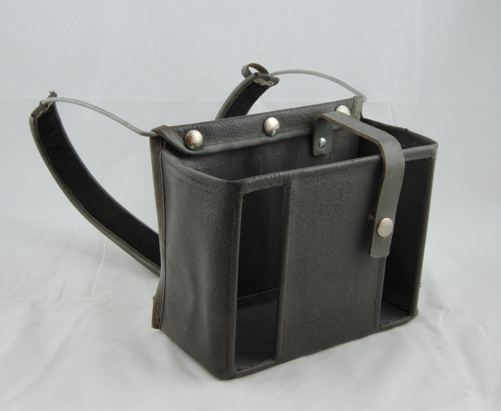 Fodral till sändare Autophon E18 HSY 20. Fodralet är i huvudsak tillverkat av ett plastliknande fuskläder med en rem av läder och tryckknappar av metall. På baksidan går två ståltrådar som är klädda och vadderade för att sändaren ska kunna bäras på magen. 

Modell/Fabrikat/typ: Autophon E18 HSY 20