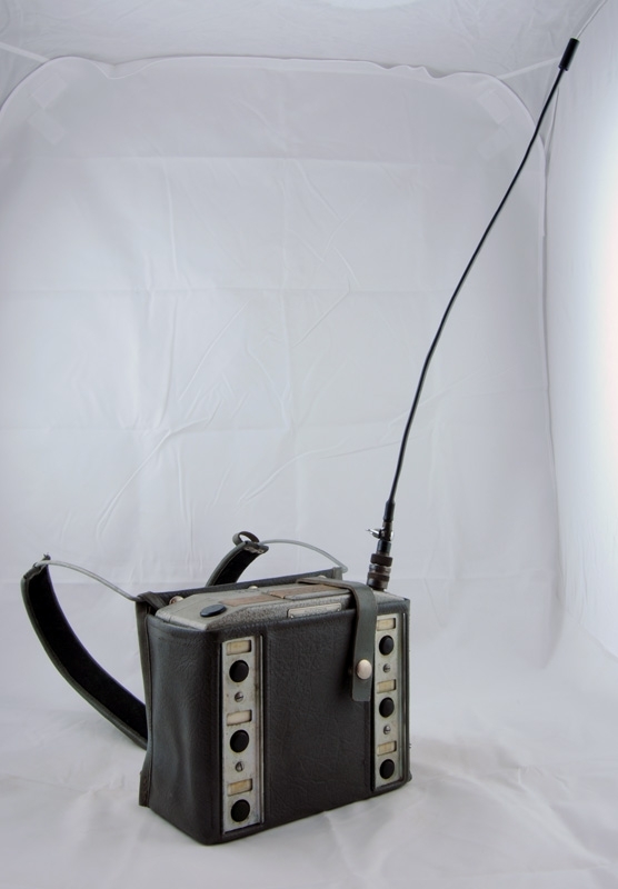 Sändare, Autophon E18 HSY 20, frekvens 154-157 MHz. Sändaren är försedd med sex tongivare för styrning av arbetsmaskiner (MATISA), Ackumulator AK 18. Märkt med svart penna ovanpå: "262", på tejp ovanpå: "2036". På framsidan två rader med tre runda svarta knappar av plast. Vänstra raden uppifrån: pil vänster, andra knappen saknar skylt, tredje knappen en stående rektangel som sitter ihop med en triangel, högra raden uppifrån pil höger, pil upp, pil ned, svart vridknapp på ovansida, antenn, vid antennen står det ”FTZ S NrQ-37/69 081746.

Modell/Fabrikat/typ: Autophon E18 HSY 20