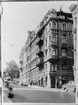 Hörnhuset Drottninggatan-Tegnérgatan före rivningen. Fasaden mot Tegnérgatan. I fonden skymtar Tegnérlunden. I hörnet Aspingtons välkända antikvariat. Foto 1959.