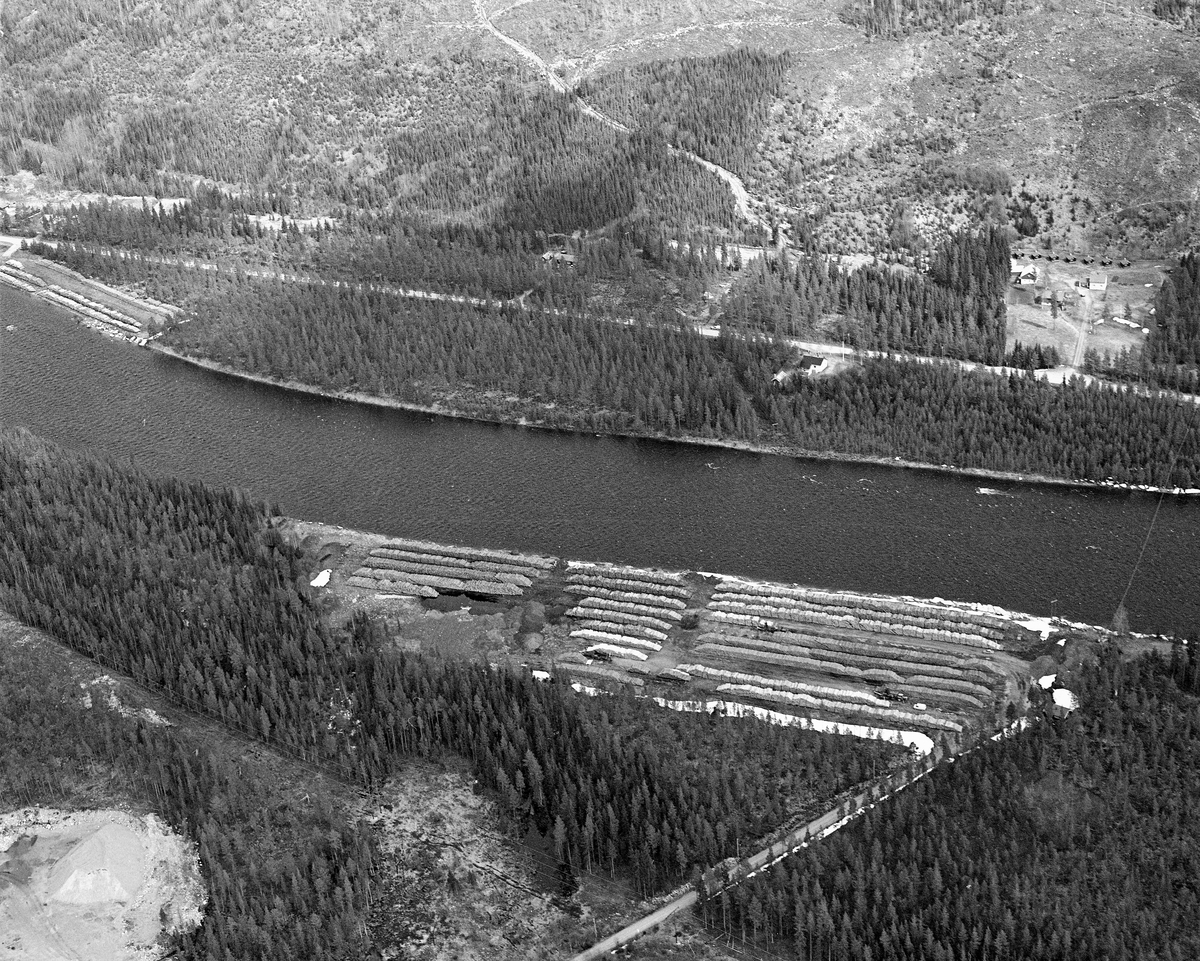 Flyfotografi, tatt over tømmerterminalene ved Trysilelva, cirka en kilometer nord for grendesenteret i Jordet i Trysil. Dette bildet er tatt fra en posisjon over den vestre elvebredden. På denne sida lå Øverengvelta, hvor tømmeret var samlet i lange lunner, der stokkene l¨noenlunde vinjelrett på strømretningen, som går fra venstre mot høyre på dette bildet. Også på den andre sida av elva, ved Furuly, var det ei tømmervelte på den smale landstripa mellom mellom elveløpet og Trysilvegen. I tillet var det en velteplass til noen hundrede meter lengre nede, som ikke er synlig på dette fotografiet. I forgrunnen ser vi et grustak. Fotografiet ble tatt i 1986.

Fra 1965 og framover fikk Klarälvens Flottningsförening opparbeidet flere terminalplasser av den typen vi ser på dette fotografiet i Trysil og Engerdal.  Slike løsninger ble mulige etter at skogsbilvegnettet i de to kommunene var blitt såpass stort at man anså det for mulig å avvikle fløtinga i de minste sidevassdragene. Omlegginga skjedde i forståelse med Trysilvassdragets skogeierforening.  Terminalplassene hadde ikke bare hjullastere, men i mange tilfeller også barkemaskiner, noe som overflødiggjorde det manuelle arbeidet med barkespader, og dermed forenklet driftsprosessene på hogstfeltene vinterstid.