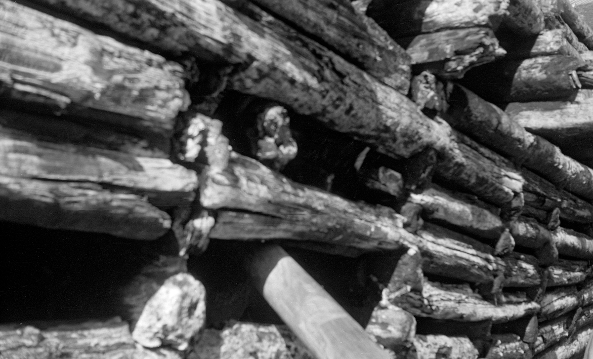 Detalj fra framveggen på Syversætredammen i elva Flisa i Åsnes i Solør, fotografert i 1955.  Bildet ble tatt i en tørkeperiode midt på sommeren, da vannføringa i elva var minimal, slik at damkonstruksjonen var godt synlig, uten overløpende vann.  Dermed ble forfallet og råteskadene på tømmerkonstruksjonen tydelige.  Den var åpenbart var moden for fornyelse.  Syversætredammen var en terskeldam som var bygd øverst i fossen, åpenbart for å skape et vannreservoar for det nedenforliggende kvernbruket, muligens også for å heve vannspeilet og lette tømmerfløtinga i det ovenforliggende elveløpet.  Dammen skapte et fall på cirka to meter.  SJF.1989-02316 viser den samme dammen mens den ennå var i god stand og på et tidspunkt da det var mye vann i Flisa.