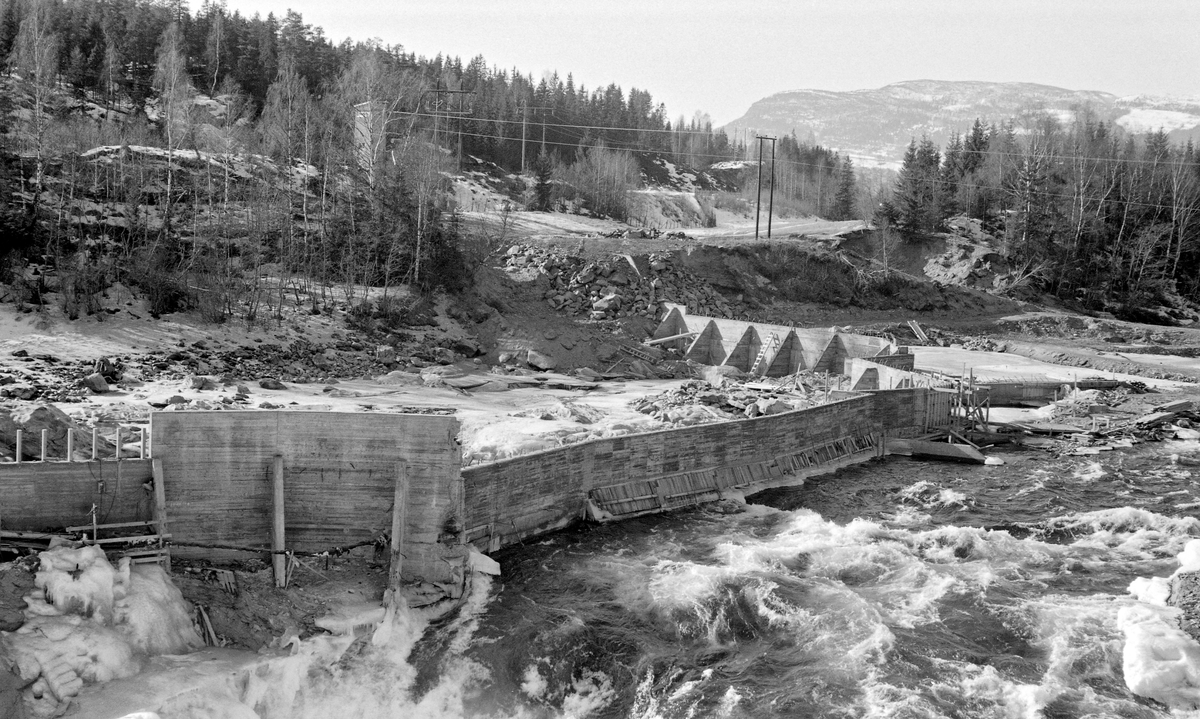 125 meter lang og 16 meter høy skådam av armert betong ved Harpefossen i Gudbrandsdalslågen i Sør-Fron.  Fotografiet er tatt vinteren 1964, mens Harpefossen kraftverk var under bygging.  Dette anlegget ble satt i drift året etter, med to kaplanturbiner som utnyttet en fallhøyde på 34 meter.