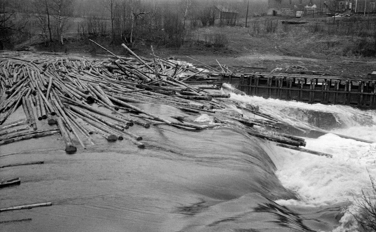 Sandsdammen ved Sandsfossen i Sandselva, et kort elveløp mellom innsjøene Råsen og Storsjøen i Nord-Odal kommune i Hedmark. Fotografiet er tatt våren 1952, da det var storflom i Sandselva. Vannet strømmet over damkrona, og med det fulgte fløtingstømmer i store mengder.  Sandsdammen var ikke bare fløtingsdam, den var også mølledam. Til høyre, nedenfor dammen, ser vi renna som førte vann til turbinen i møllebygningen.

De store tømmermengdene vi ser på fotografiet kom etter at lensa ved Mørkåas utløp i Råsen hadde sviktet under en kraftig regnflom. Store mengder vann og tømmer ble ansett for å være en fare for dammen - se fanen «Opplysninger».