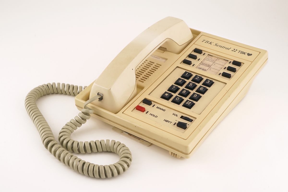 Telefonapparat med taster nummerert fra 0 til 9 og med firkant- og stjernetast. Telefonrør  er tilkoblet med spiralisert ledning. Apparatet er utstyrt med 6 knapper for forhåndsinnstilling av telefonnummer. Videre er det knapper for minne, hold- og høyttalerfunksjon. Volumbryteren er et rullehjul. Fra undersiden kan man dra ut et plastkort/telefonliste. 

I tillegg medfølger to  instrumentbokser med mulighet for å  ta opp og lagre samtaler. I front på den ene er det et vindu med antatt digital tekst og diverse  "softtouch" knapper til å bearbeide opptak. To brytere for antatt å kunne justere lydstyrken. Videre er det montert ulike  utganger for tilkobling av diverse utstyr bl.a. headset. Det er også montert en diskettstasjon med åpning i front. På baksiden av opptakeren er det montert ulike dataporter og strømtilkoblinger. Jordingskabel med skjøtekobling. Strømkabel medfølger.

Den andre boksen er forsynt med to håndtak i front, samt en luke/deksel på venstre side, med gjennomsiktig vindu av plast,  som kan åpnes for isetting av kasettbånd. På høyre side i fronten er det et gjennomsiktig rødt plastvindu hvor det er gjort hull slik at man kommer til en hvit trykkbryter. Fronten er videre påsatt en blå, vridbar bryter, en hvit vippebryter med rød og grønn lampe, samt fire sorte trykkbrytere med hvit tekst: "START" "STOP" og høyre/venstre pil. Nederst er det en sort trykkbryter som formentlig benyttes til å åpne dekslet til kasettbåndet.Til høyre for denne bryteren er det et kontaktpunkt for tilkobling av tilleggsutstyr.
På baksiden av boksen er det fire ulike kontaktpunkter for tilkobling av tilleggsutstyr samt fastmontert strømkabel med kontakt. Videre er det montert en skrubar sikringsholder.
Under boksen er det montert fire, høydejusterbare, ben