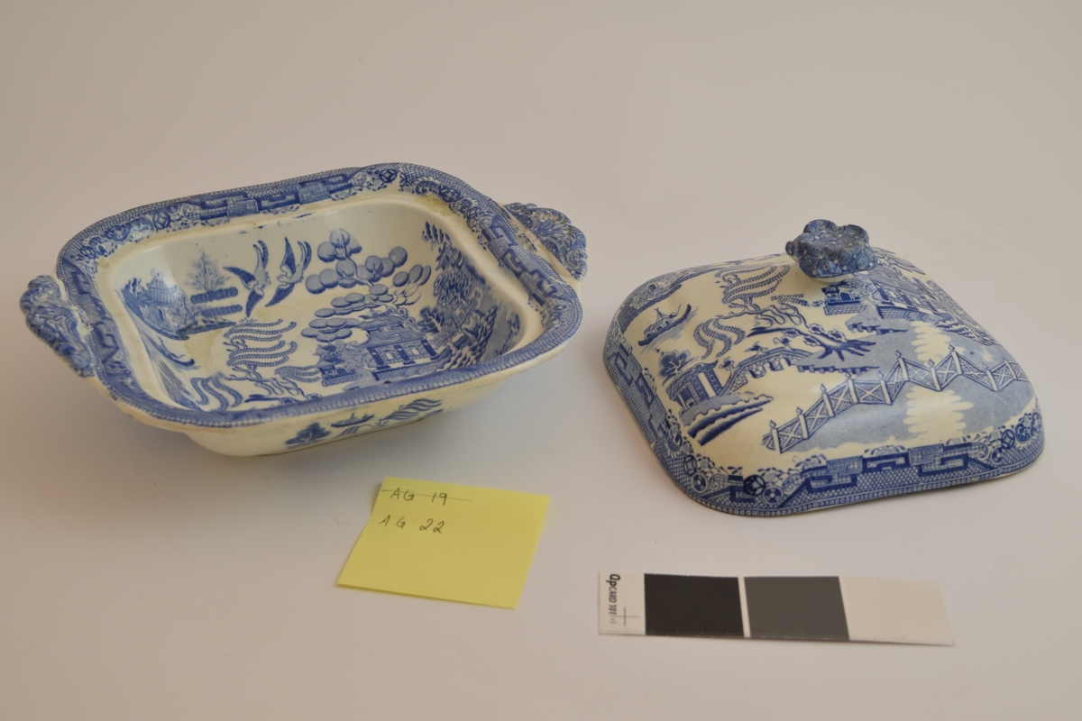 Fayanese lokkefat, leirgods med tinnglasur. Dekorert med en scene som framstiller flere hus, en elv, ett gjerde og dyr og planter. Stilen på dekorasjonen er asiatisk insprirert.