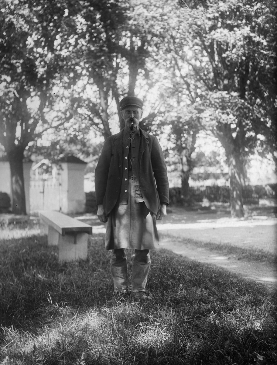 "Kyrkvaktar Alström Simtuna med kyrkgrindarna bakom", vid Simtuna kyrka, Uppland 1921