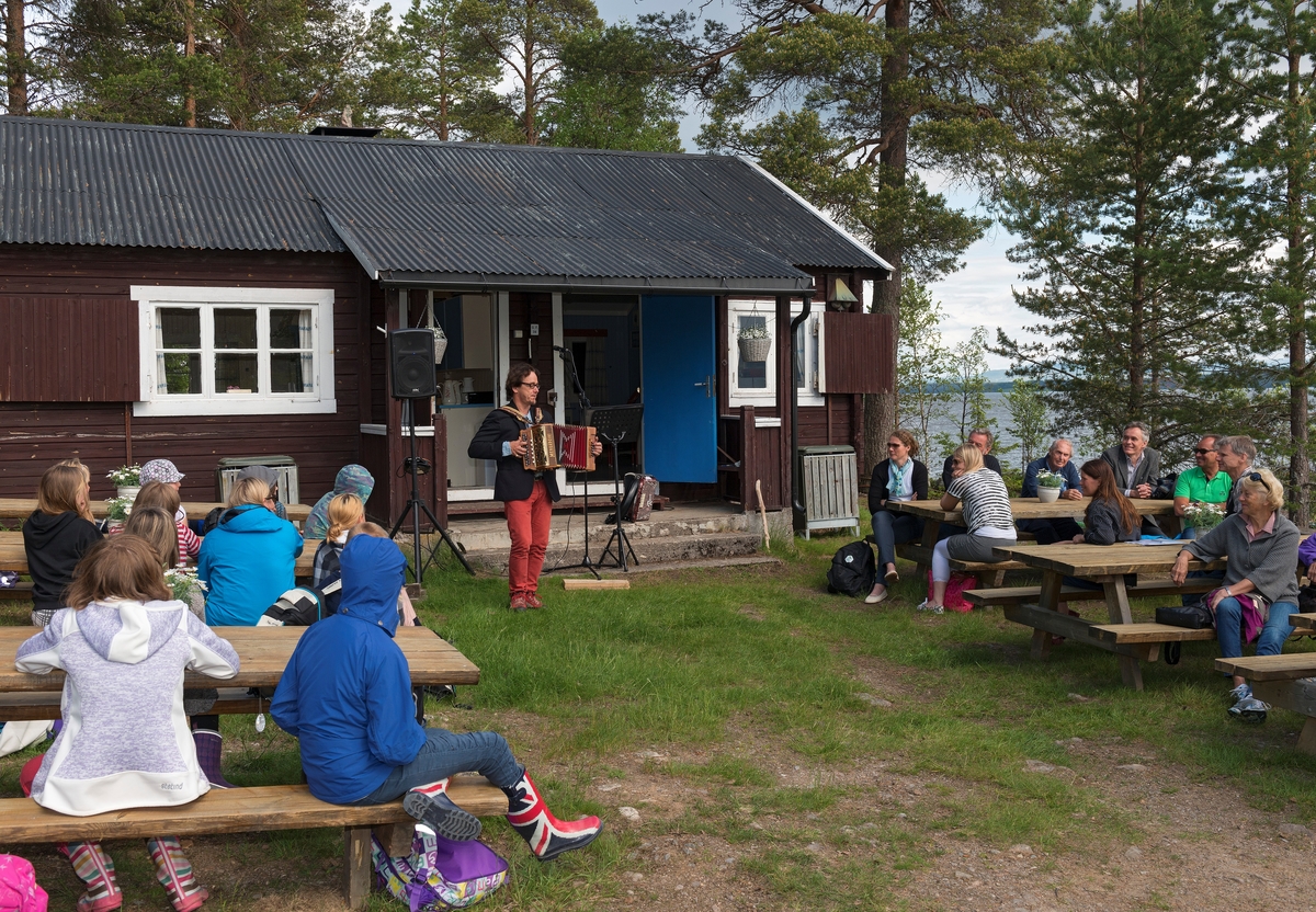 Fra arrangementet i forbindelse med 100-årsjubileet for slepebåten «Trysilknut» ved Sørlistøa fløtermuseum ved Osensjøen i Åmot 11. juni 2014.  Fotografiet er tatt på sletta foran huset museet bruker som kafé- og resepsjonslokale, men som opprinnelig inneholdt mannskapsrom og kontor for fløtersjefen.  I forgrunnen sitter elever og personale fra Osen oppvekstsenter, som var spesielt invitert til arrangementet.  Lengre bak sitter et mer voksent publikum.  Da dette fotografiet ble tatt underholdt musikeren Lillebror Vasaasen med toradertrekkspill og sang fra en posisjon framfor trappa til det nevnte huset.  Jubileumsarrangementet samlet drøyt 30 deltakere. 

Tormod Lillebror Vasaasen skrev følgende visetekst til slepebåten Trysilknuts 100-årsjubileum:

Sjå båten som vugger og mænnskapet med, ja sjå
folket som samle seg opp, 
sjå ællesom juble og haste av sted, utpå
Osensjø’n helt uta stopp.

Ref.:
Dæ’ er da så vakkert på vår vesle jord, je
ser da et flagg vaie fritt der om bord,
om ælle fækk kjinne og ælle fækk sjå slik ei 
perle som legg ut frå lænd.

Hør motor’n som dure sin grommeste lyd og hør 
skovla som banke og slår,
Hør folket som tala og flire i fryd, der dom 
lent over rekkverket står.
Refr. ...

Kjinn lufta ta kafe og pultost og brød og hør
fugla som kjæm helt frå sør,
Kjinn sola som vermer så kjækan blir røu
og sjå sola som går ner og blør.
Refr. ...

Føl båten som legg ut frå strænda vi står og sjå
bøljen som slår i mot lænd,
Føl stolthet og varme frå fortia vår og sjå
fløter’n som arbe’ de’n kæn
Refr. ...

Mer informasjon om båten Trysilknut finnes under fanen «Andre opplysninger».