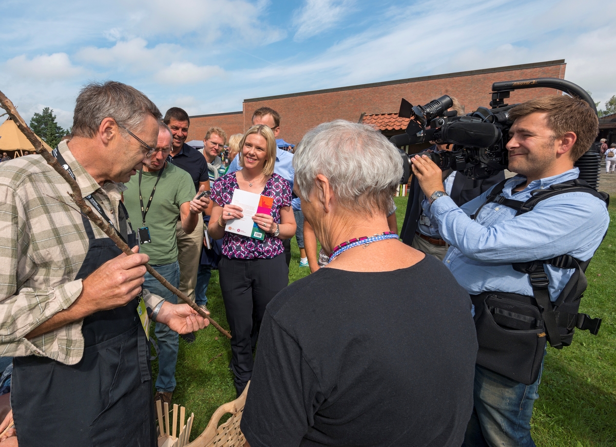 Fra det såkalte «håndverkstorget» under De nordiske jakt- og fiskedager på Norsk Skogmuseum i Elverum 7. august 2014.  I forgrunnen ser vi (til venstre) tradisjonshåndverkeren Samson Øvstebø fra Åkra i Kvinnherad og husflidskonsulent Magnhild Tallerås (til høyre, med ryggen mot fotografen).  Øvstebø holder en einerkvist i hendene.  Kvisten er et av emnene til ei kipe, et flettet bæreredskap, som bøndene på Vestlandet brukte til å bære alt fra epler til tørr husdyrgjødsel.  Under jakt- og fiskedagene i 2014 tilbød Samson Øvstebø to dagskurs i kipebinding.  Her forteller han deltakere fra seminaret «Gull og grønne skoger – nye grep for å øke skogens verdi og glede for alle» – med landbruks- og matminister Sylvi Listhaug fra Fremskrittspartiet i spissen – om håndverket sitt.  De andre personene bak Øvstebø og Tallerås er (fra venstre) journalist Per Magnussen fra avisa Østlendingen, stortingsrepresentant Gunnar A. Gundersen fra Hedmark Høyre, stortingsrepresentant Tor André Johnsen fra Hedmark Fremskrittsparti og Kersti Grindalen fra Elverum Fremskrittsparti (som vi bare ser håret og kinnet til).  Administrerende direktør Erik Lahnstein i Norges skogeierforbund er delvis skjult bak landbruks- og matstatsråden.  Fjernsynsfotograf Olav T. Hustad Wold fra TV2 dokumenterte møtet mellom tradisjonshåndverkerne og politikerne fra en posisjon til høyre i bildet.