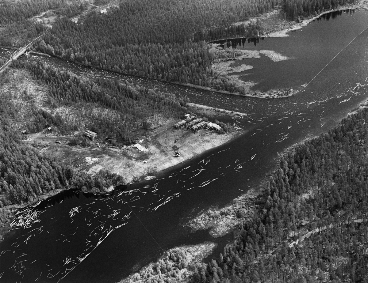 Flyfotografi fra Osøra i Åmot i Hedmark, tatt i mai 1984, den siste sesongen det var tømmerfløting i denne delen av Glommavassdraget.   Sentralt i bildeflata ser vi hvordan elva Søndre Osa renner inn i elva Søndre Rena, i den nordøstre enden av den oppdemte Løpsjøen.  Begge elevene var tømmerførende på det tidspunktet da fotografiet ble tatt.  På moen der de to elvene møtes ser vi ellers en velteplass – en tømmerterminal.  Hit ble det transportert tømmer med lastebiler fra hogstfelt som lå vanskeligere til i forhold til fløtingsvassdraget.  Tømmeret ble slått på vannet ved hjelp av digre anleggsmaskiner når vannføringa høvde for fløting.  Da dette fotografiet ble tatt lå det fortsatt en del virke i digre velter på land, klare for utislag.  Øverst i bildets venstre hjørne skimter vi fagverksbrua i stål hvor Riksveg 215 krysset Søndre Osa.