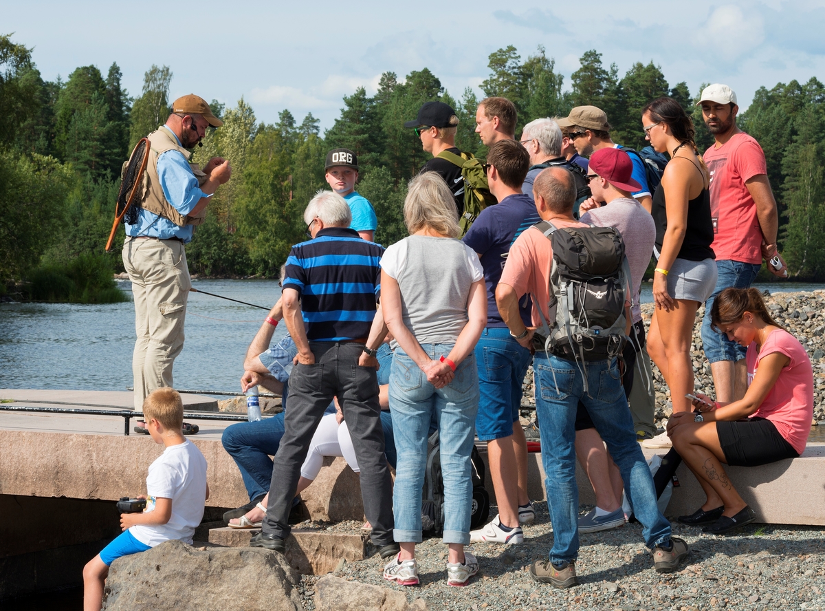 Tore Litleré Rydgren viser fluefiske fra brygga i Elveparken på Norsk Skogmuseum under De nordiske jakt- og fiskedager 2014.  Rydgren var utstyrt med en liten mikrofon på ei bøyle foran munnen og en høyttaler, slik at han kunne introdusere utstyret og fisketeknikkene for sine tilhørere under et arrangement der det var mange lydinntrykk som konkurrerte om publikums oppmerksomhet.