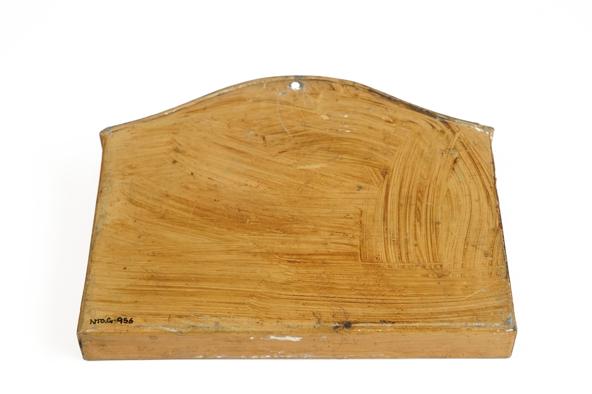 Bemalt metallboks med åpning i toppen for isetting av dokumenter. Ryggen på kassen er oppoverbuet med hull for montering på vegg.