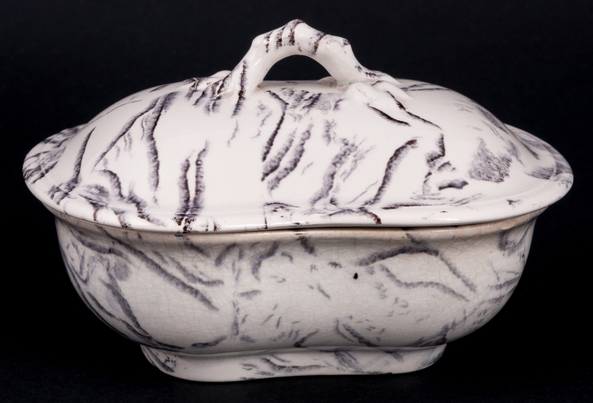 Tvättservis av vitt porslin med marmorering i grått. Servisen består av handfat, potta, en avlång tvålkopp och en kvadratisk, båda med lock. Handfatet stämplat Gustafsberg.