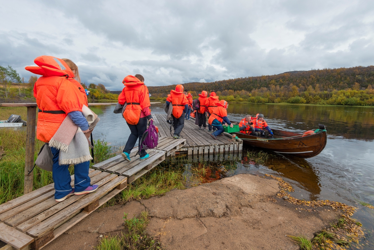 Delegasjon fra Norges vassdrags- og energidirektorats (NVSs) museumsordning på vandring mot elvebåt, som firmaet Cavzo Safari bruker i sitt opplevelsestilbud på Kautokeinoelva/Guovdageaineatnu i Finnmark.  Sikkerheten var ivaretatt ved at gjestene var iført oransje redningsvester.